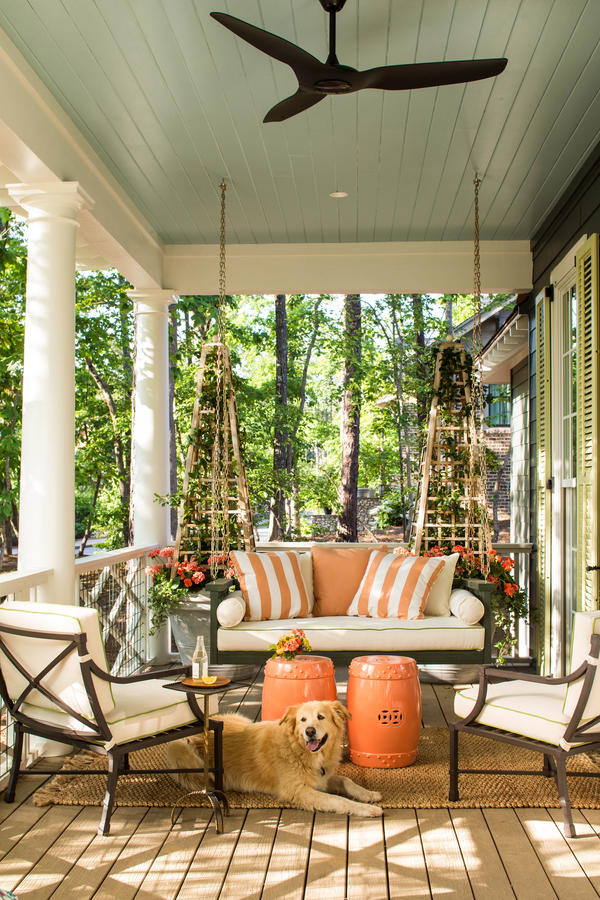 Comfy lounging porch with big bed swing and pops of orange accents www.PattersonDecoratingGroup.com/blog