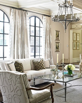 This spacious family room has dramatic arched French doors that are draped in a beautiful neutral fabric with a large scale pattern and contrast trim. www.PattersonDecoratingGroup.com/blog