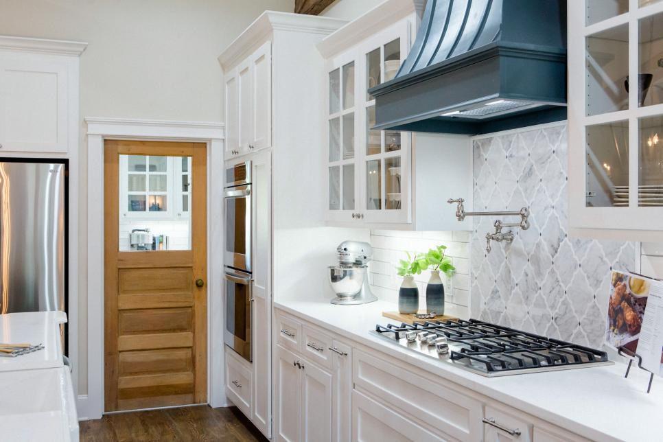 Clean fresh kitchen with white cabinetry stone countertops and gray tile backsplash www.PattersonDecoratingGroup.com/blog