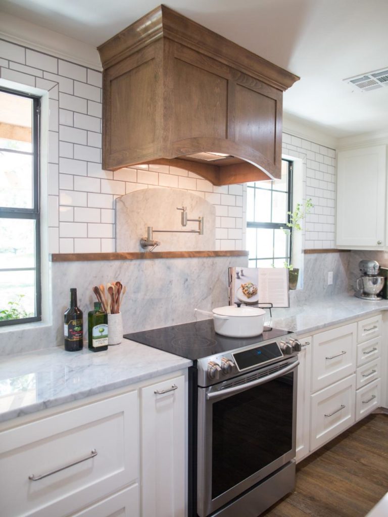 Fixer Upper Kitchen with white tile and gray marble countertops warmed up by a wood hood vent and trim in the Prickly Pear House www.PattersonDecoratingGroup.com/blog