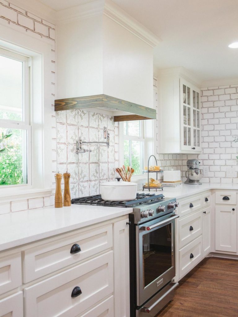 Fixer Upper Worm House Kitchen features white cabinetry, subway tile and countertops while the wood island warms up the space wwww.PattersonDecoratingGroup.com/blog