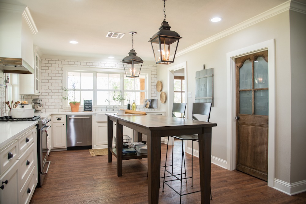 The antique wood door warms up the mostly white Fixer Upper kitchen www.PattersonDecoratingGroup.com/blog