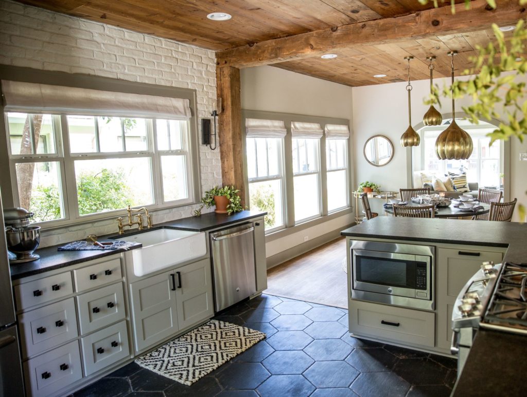 This Fixer Upper kitchen includes enlarged windows to bring in more natural light, black stone countertops and a farmhouse sink www.PattersonDecoratingGroup.com/blog